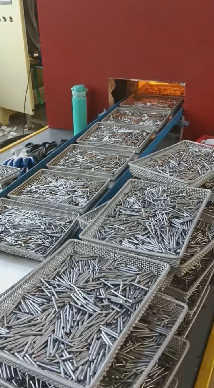 Trays of elongated metal components beside the furnace conveyor