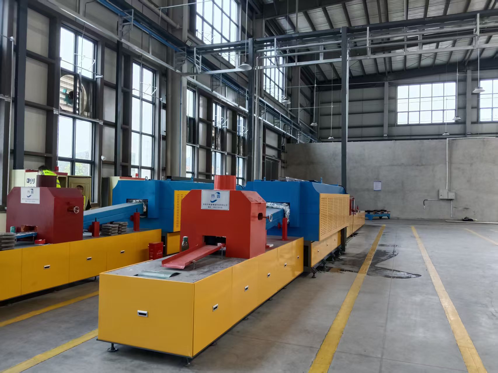 Blue and yellow continuous furnace equipment installed in a customer workshop